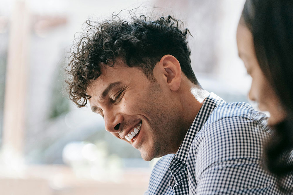 Deux collaborateurs souriants en échange autour d'une tablette, illustrant la définition et la pratique de l'AFEST avec Les 2 Rives